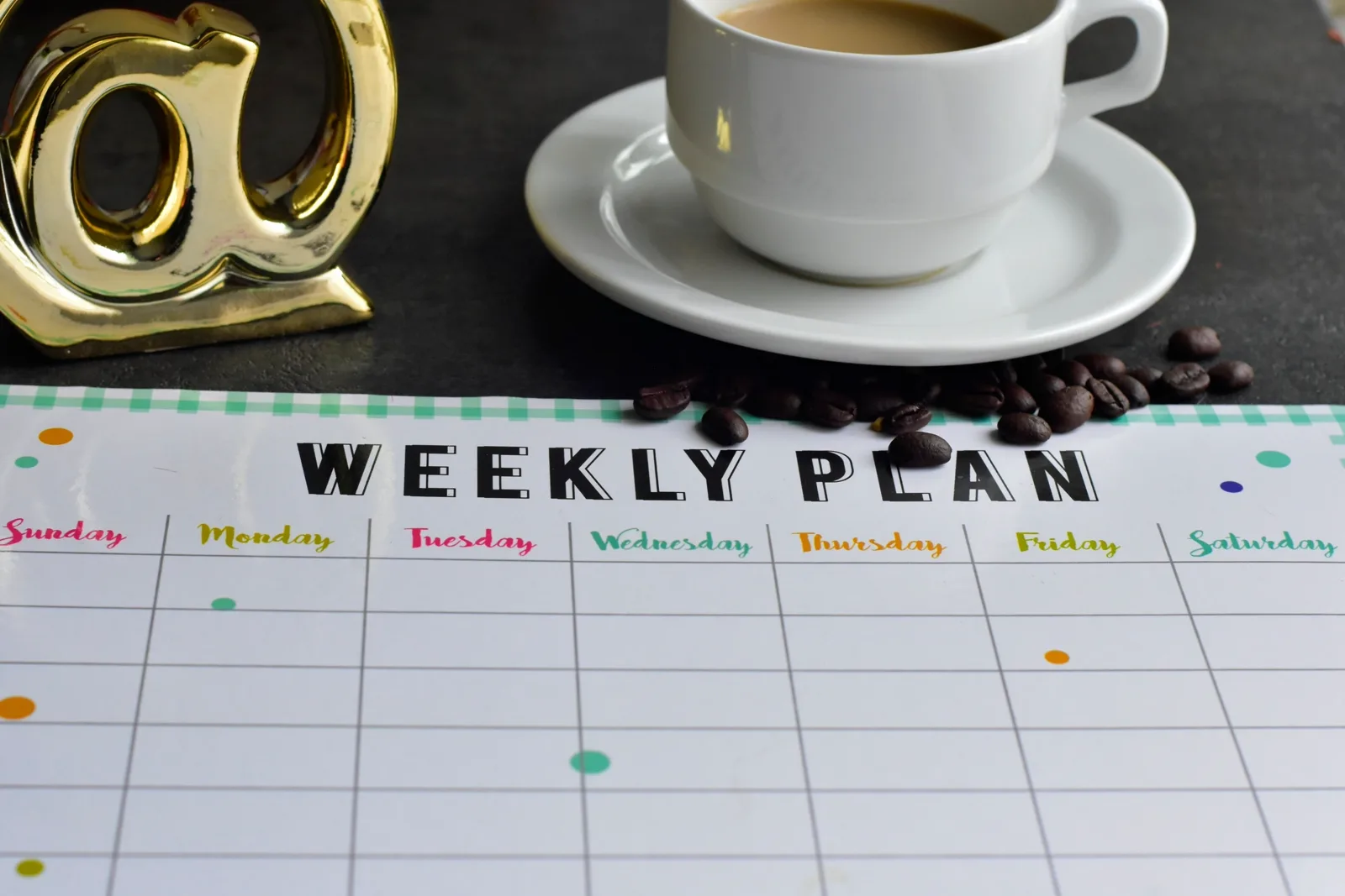 A weekly planner with time blocks marked out beside a coffee cup