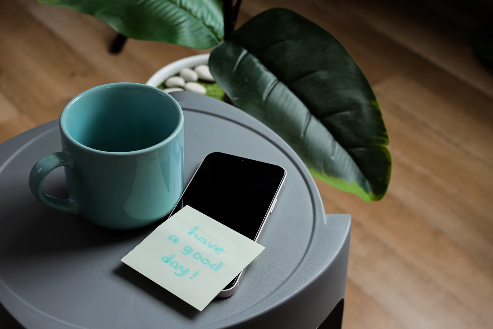 A short quote written by hand on a small card propped against a mug on a desk
