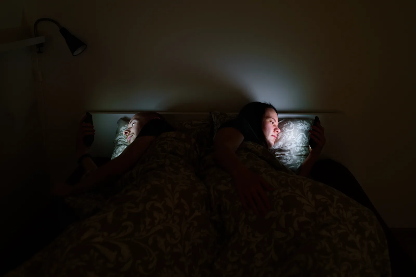 A dark bedroom with a face lit by phone glow late at night
