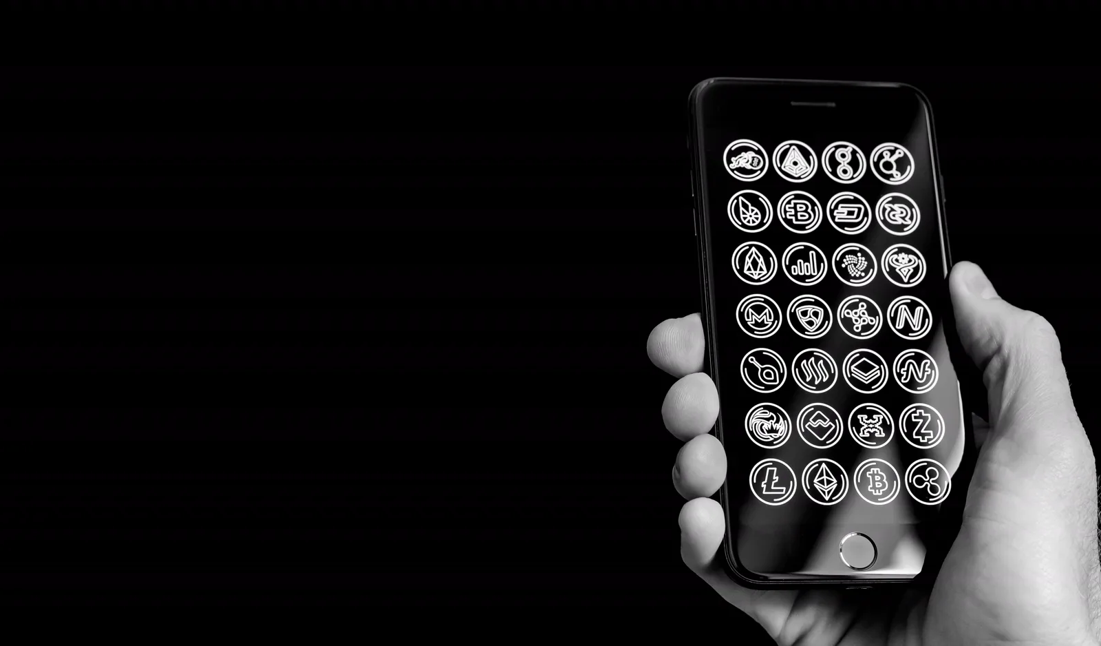 A hand holding a grayscale phone, colorless app icons