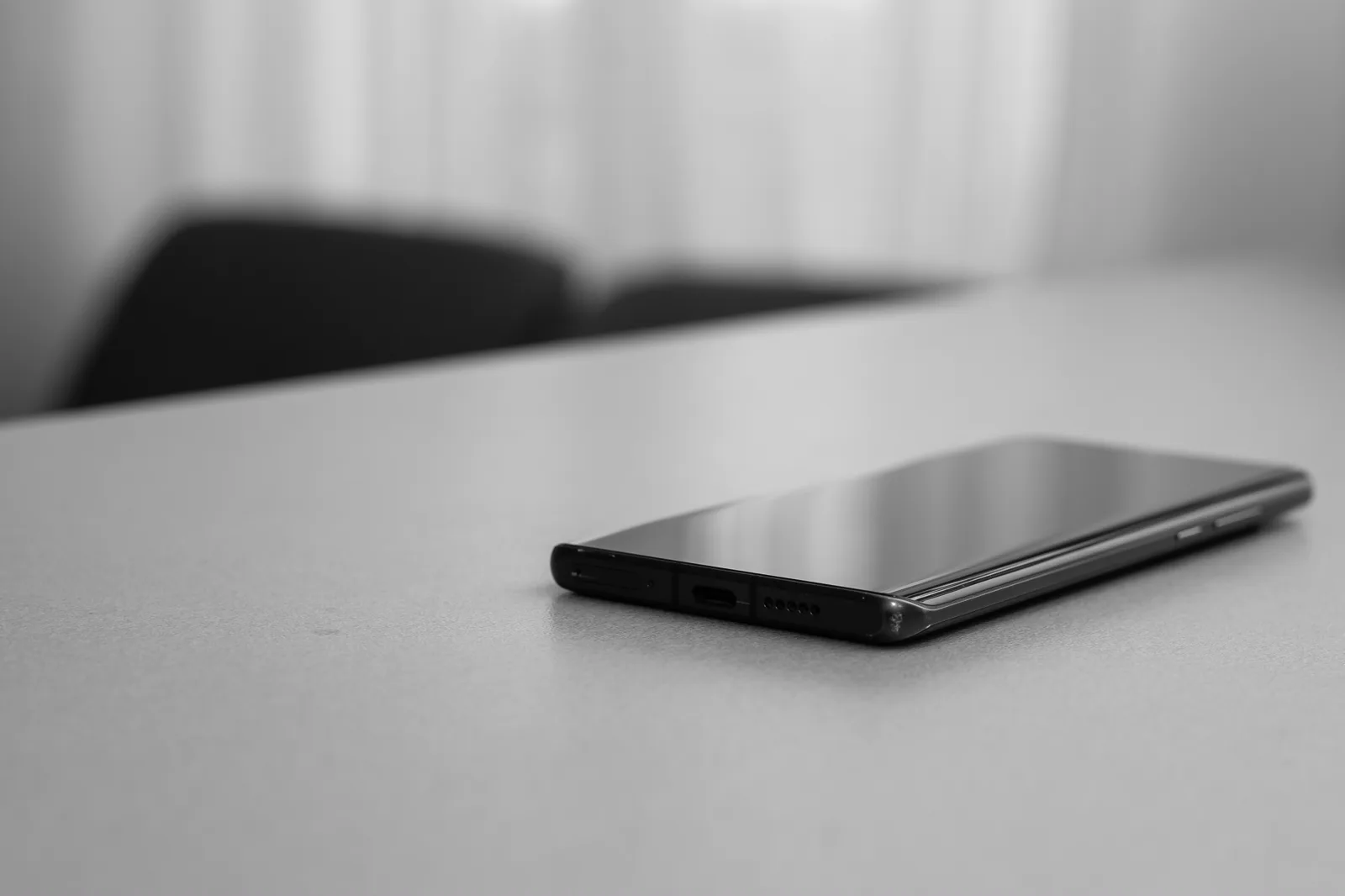 A phone in grayscale on a table, calm and unremarkable